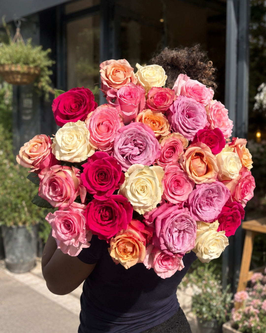 Bouquet de roses multicolores tenu par une fleuriste